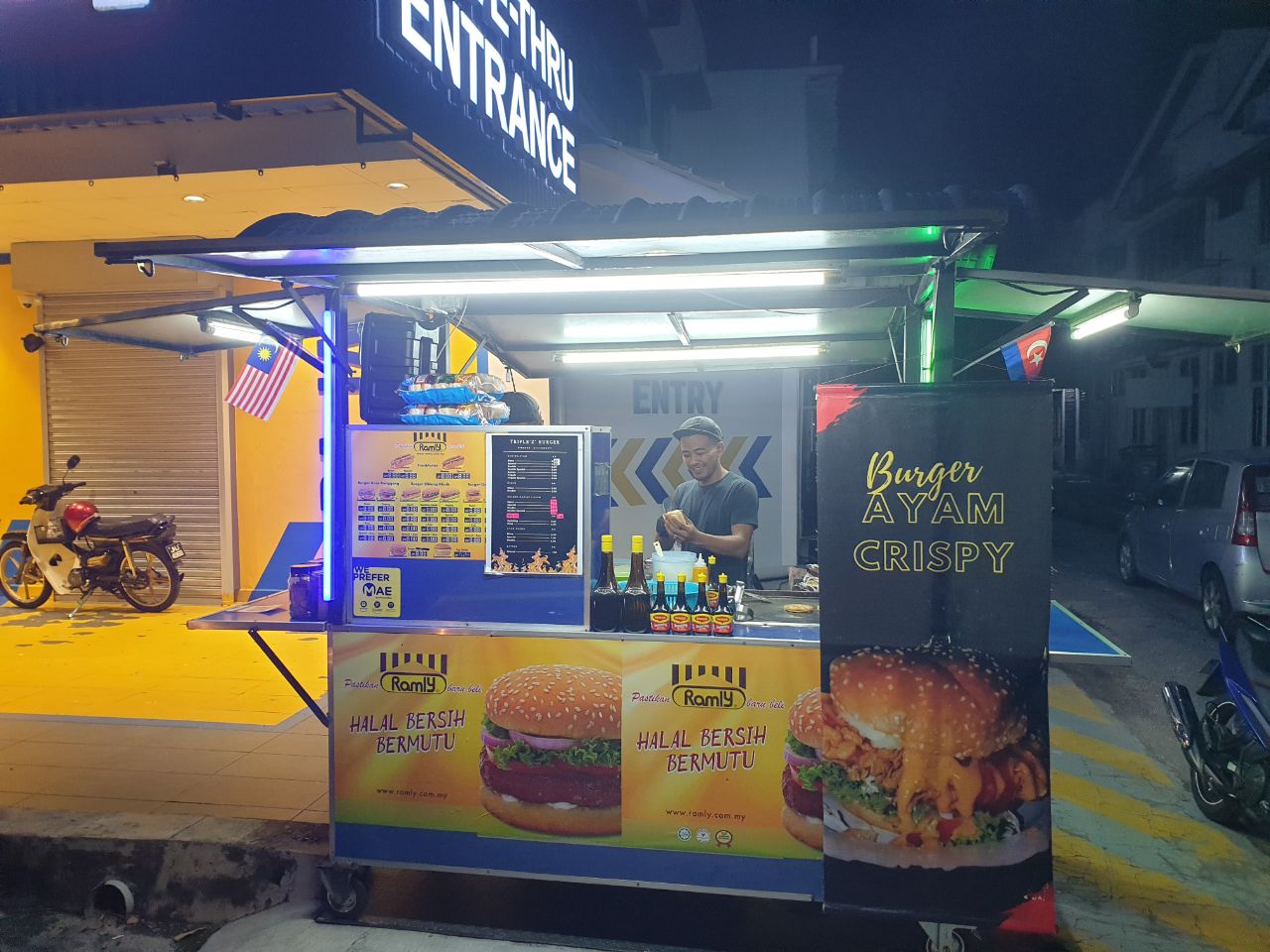 Gambar gerai burger di Taman Universiti yang menjual pelbagai jenis burger, termasuk burger daging lembu, ayam, dan kambing.