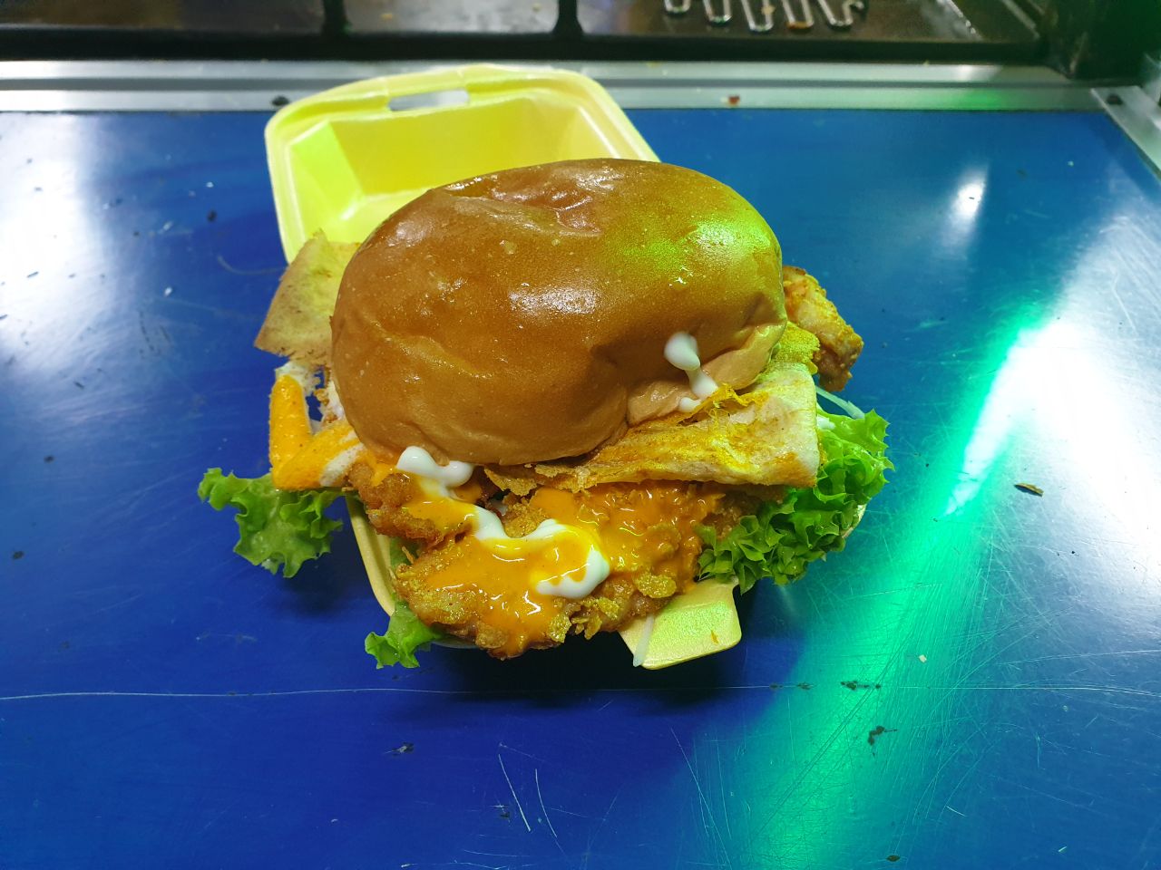 Gambar burger ayam crispy dari gerai burger di Taman Universiti dengan ayam goreng rangup dan bahan-bahan segar.